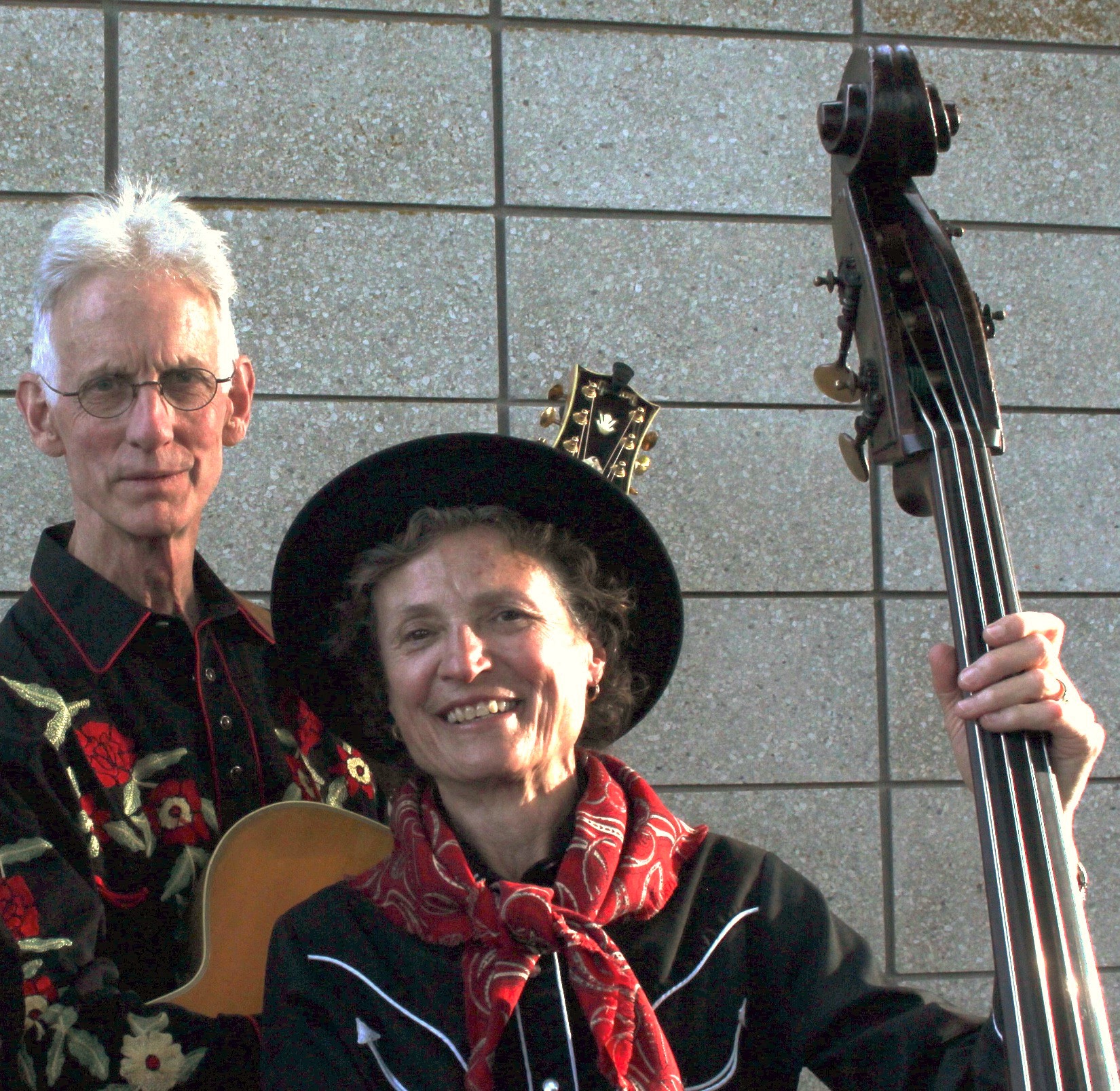 downundermutts man and woman dressd in cowboy shirts. They hold a double bass and a vintage acoustic guitar